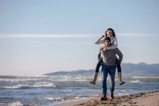 couple having fun at beach during autumn Men Giving Piggy Back Rides his girlfriend At Sunset By The Sea, autumn time ,model released, Symbolfoto Copyright: xZoonar.com benisxarapovicx 12518881 ,model released, Symbolfoto ,property released