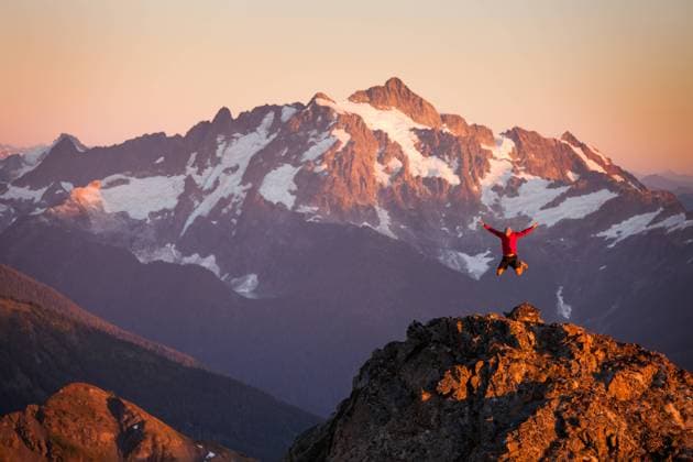 A hiker jumps off rocky cliff in North Cascades National Park. Glacier, Washington, United States CR_JDIP240227-1346428-01 ,model released, Symbolfoto