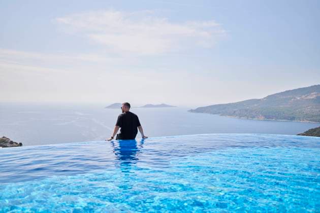 Creative Highlights Symbolbilder Man looking at sea sitting on the edge of swimming pool at villa model released, Symbolfoto property released, ANNF00828