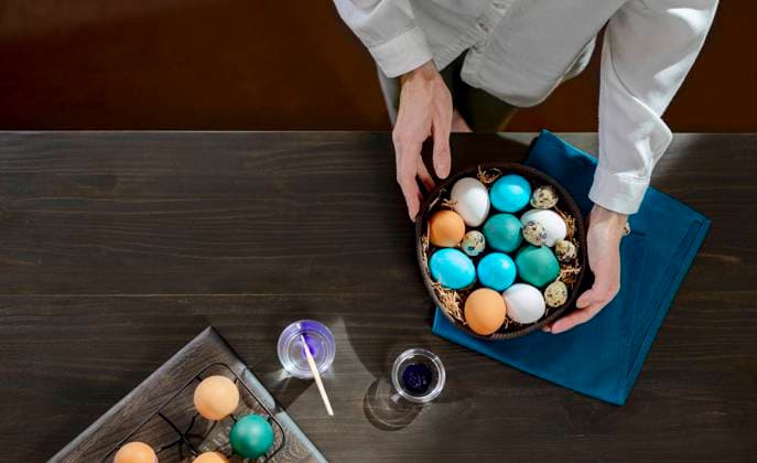 Woman with basket of colorful easter eggs on table at home model released, Symbolfoto, MBLF00253