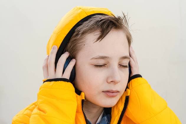 Creative Highlights Symbolbilder A contemplative young boy in a striking yellow jacket enjoys music on his headphones against a soft neutral background Model Released AnnaBogush_ID19410_575268_003 Copyright: xAnnaxBogushx