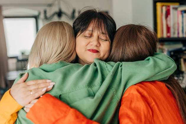Smiling mother embracing daughters at home model released, Symbolfoto, VSNF01667