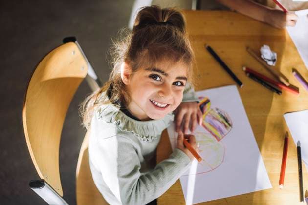 Creative Highlights Symbolbilder High angle view of smiling girl drawing with crayon on paper while sitting at bench in classroom Sweden, Stockholm, model released, property released Copyright: xMaskotx , MA107357 MA107357