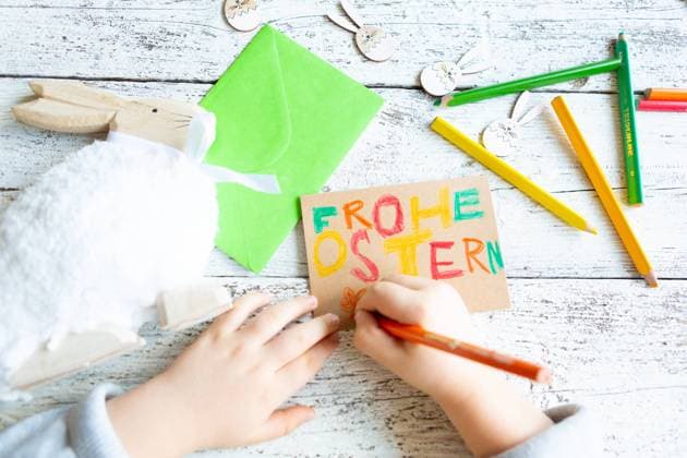3 March 2024: Child making Easter decorations, hand writing with colored pencils: Happy Easter *** Kind beim Basteln von Osterdekoration, Hand schreibt mit Buntstiften: Frohe Ostern