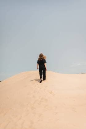 Creative Highlights Symbolbilder Back view of woman hiking up sand dunes with hair flowing in the wind Sawyer, Michigan, United States CR_AKAO240307C-1365424-01 ,model released, Symbolfoto