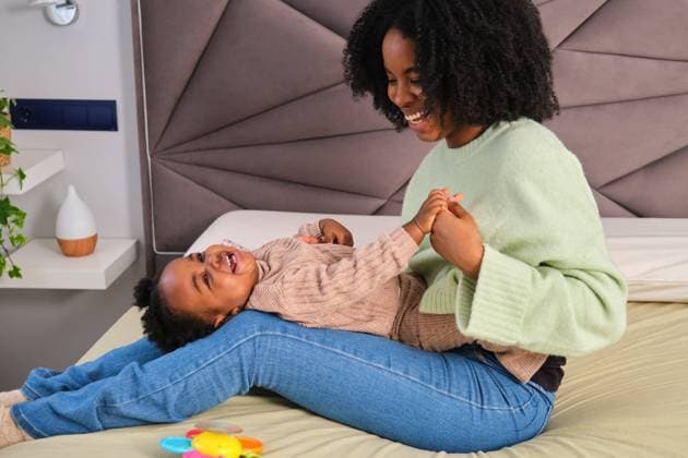 Cuban mother tickled her toddler daughter who is laughing on bed. Madrid, Community of Madrid, Spain CR_CRVI240306-1363182-01 ,model released, Symbolfoto