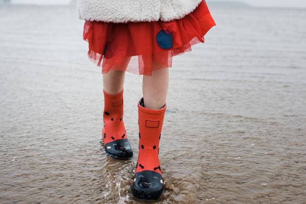 Creative Highlights Symbolbilder child s red spotted rain boots in the water with red dress and coat Poole, England, United Kingdom R_RABE220105-892514-01 ,model released, Symbolfoto