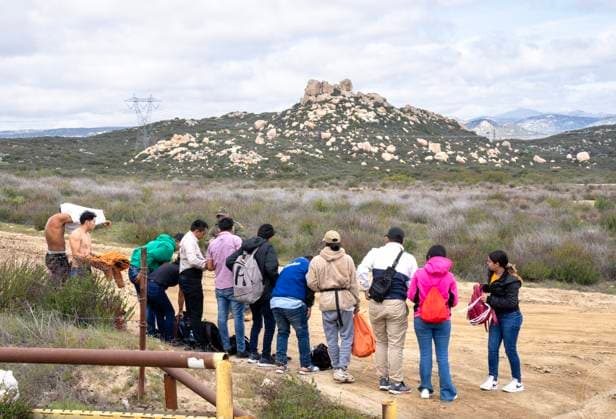 Migrants wait to surrender to the U.S. Border Patrol after crossing the border wall from Mexico near Campo, California, about 50 miles from San Diego, on Wednesday, March 13, 2024. A bipartisan Senate immigration bill to address the migrant immigration issue is stalled in the House due to election year politics.  CAL2024031409 PATxBENIC