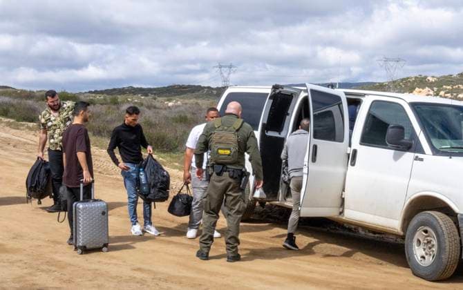 Migrants are placed into vans by the U.S. Border Patrol after crossing the border wall from Mexico near Campo, California, about 50 miles from San Diego, on Wednesday, March 13, 2024. A bipartisan Senate immigration bill to address the migrant immigration issue is stalled in the House due to election year politics.  CAL2024031418 PATxBENIC