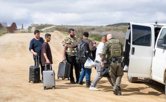 Migrants are placed into vans by the U.S. Border Patrol after crossing the border wall from Mexico near Campo, California, about 50 miles from San Diego, on Wednesday, March 13, 2024. A bipartisan Senate immigration bill to address the migrant immigration issue is stalled in the House due to election year politics.  CAL2024031416 PATxBENIC