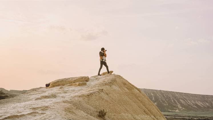 Creative Highlights Symbolbilder A solitary hiker stands atop a cliff in Bardenas Reales, Navarra, Spain, capturing the serene beauty of the sunset. Model Released AlexBascuas_ID20181_597228_007 Copyright: xAlexxBascuasx
