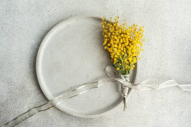 Top view of delicate arrangement of vibrant mimosa flowers tied with a silver ribbon, presented on a sleek, textured table surface for a sophisticated touch Model Released AnnaBogush_ID20290_600340_004 Copyright: xAnnaxBogushx