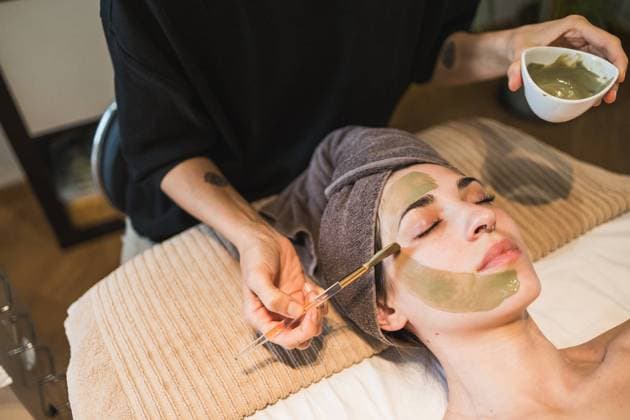 A tranquil scene of a woman getting a green facial mask applied by a beautician in a serene spa setting Model Released DavidMunoz_ID20205_597901_031 Copyright: xDavidxMunozx