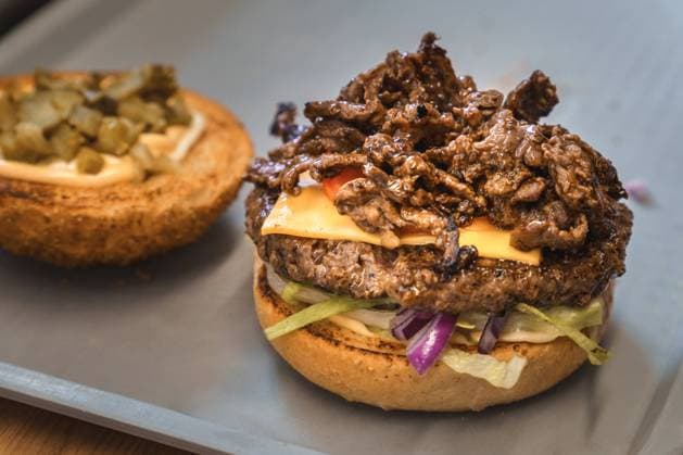 Schwabmünchen, Bavaria, Germany - March 17, 2024: Prepared Philly cheese burger on a tray in a snack bar with fresh beef, tomato, lettuce and toasted hamburger bun *** Zubereiteter Philly-Cheese-Burger auf einem Tablett in einem Imbiss mit frischem Rindfleisch, Tomate, Salat und geröstetem Hamburger Brötchen