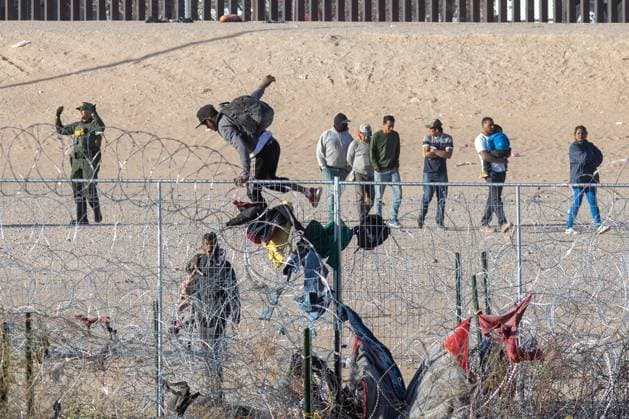 March 15, 2024, Auburn Hills, Michigan, USA: Two men scale the cyclone fence installed by the Texas National Guard as hundreds of migrants queue up along the border wall dividing Mexico and the United States, awaiting processing by the Border Patrol in hopes of receiving asylum. Auburn Hills USA - ZUMAp241 20240315_zip_p241_007 Copyright: xDavidxPeinadox