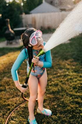 IMAGO Creative, Sommer, Sommertage im Garten IMAGO Creative, Jahreszeit Sommer, Sommerferien Close up of young girl in swimsuit drinks water from hose in backyard Sioux Falls, South Dakota, United States CR_ASWE240317-1369079-01 ,model released, Symbolfoto ,property released