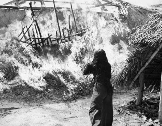 VIETNAM WAR: BURNING HOME. Near An Khe, a Vietnamese woman attempts to save her house burnt by the U.S. First Cavalry Division on a search and destroy mission. Photograph, 1965-1966.  Copyright: xGRANGERx xGRANGERx 0045178