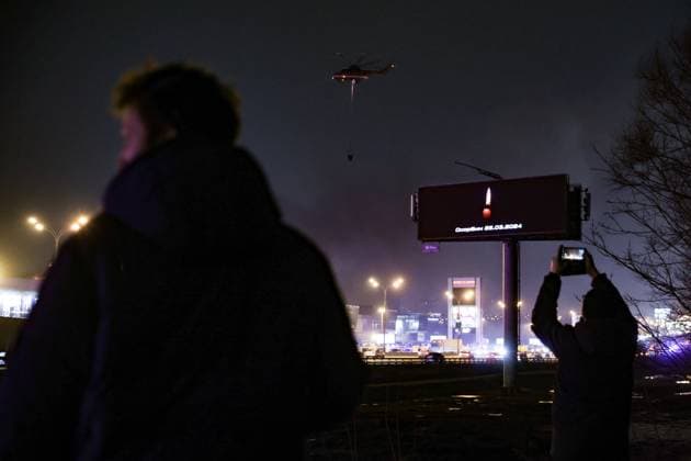RUSSIA, MOSCOW REGION - MARCH 23, 2024: A person takes picture of a billboard poster reading We Mourn 22.03.2024 after a terrorist attack at the Crocus City Hall in the town of Krasnogorsk, where several unidentified gunmen opened fire on people before the start of a performance. Mikhail Tereshchenko TASS  68462454