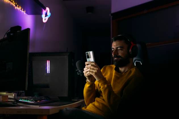 IMAGO Creative, Lifestyle, Gaming Influencer using smart phone near desktop PC at home model released, Symbolfoto property released, EGHF00828