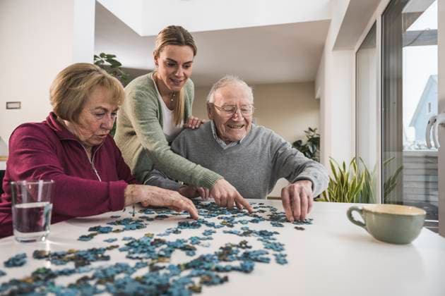 Happy home caregiver playing puzzle game with senior couple model released, Symbolfoto property released, UUF31171