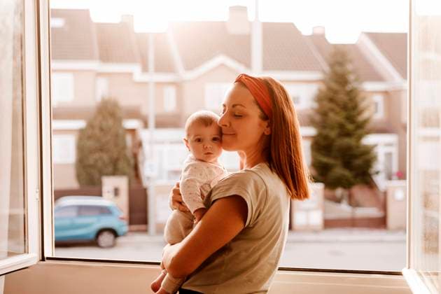 Mother with eyes closed embracing baby daughter near window model released, Symbolfoto property released, EBBF08743
