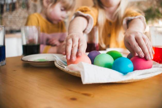 Girl arranging colorful Easter eggs in plate on table at home model released, Symbolfoto property released, ASHF00056
