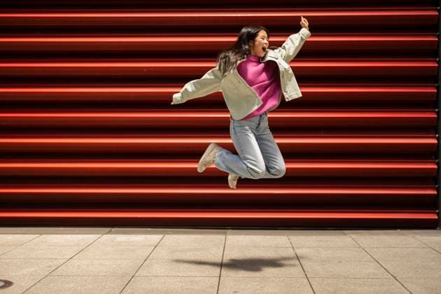 Creative Highlights Symbolbilder Happy young woman jumping in front of shutter model released, Symbolfoto, JCCMF11409