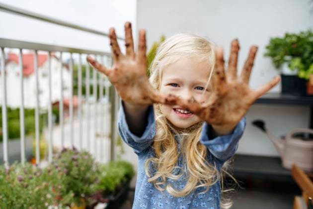 Creative Highlights Symbolbilder Smiling girl showing hands covered in dirt at balcony model released, Symbolfoto property released, NSTF00008