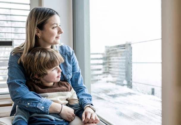 Smiling mother and son looking through window at home model released, Symbolfoto property released, UUF31400