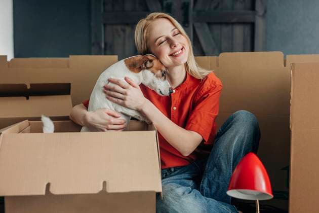 Creative Highlights Symbolbilder Happy woman embracing dog near cardboard boxes at home model released, Symbolfoto property released, VSNF01677
