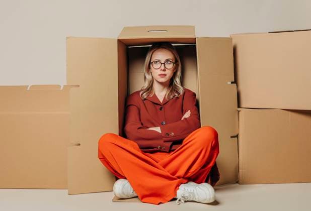 Creative Highlights Symbolbilder Upset businesswoman sitting with arms crossed in carton box against white background model released, Symbolfoto, VSNF01724