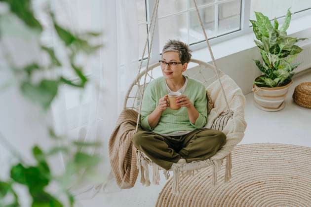 Mature woman having tea on hanging chair at home model released, Symbolfoto property released, YTF01952