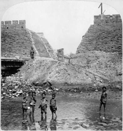 CHINA: BEIJING, c1902. The aftermath of the Boxer Rebellion: a break in the outer wall and destruction of the temporary railway for bringing supplies into the city, with five children in the water in the foreground and an Indian soldier standing guard on the railroad tracks in the background. Stereograph, c1902.  Copyright: xGRANGERx xGRANGERx 0116787