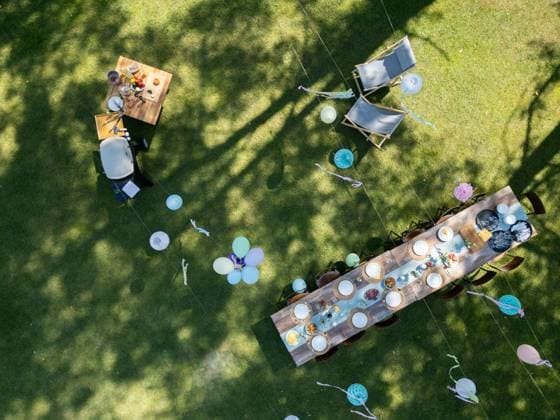 Top view of summer garden party in a beautiful garden. BBQ family gathering with a set table and colorful decorations. Top view of summer garden party in a beautiful garden. BBQ family gathering, with a set table and colorful decorations. model released
