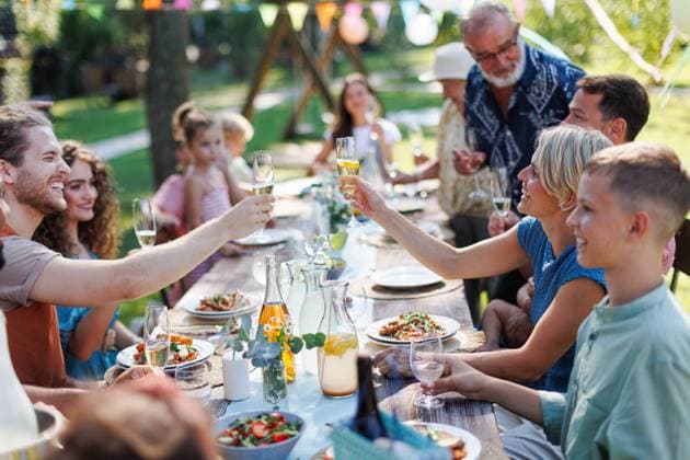 Family clinking glasses at summer garden party. Celebratory toast at the table. Family and friends clinking glasses at summer garden party. Celebratory toast at the table. Big family garden bbq. model released