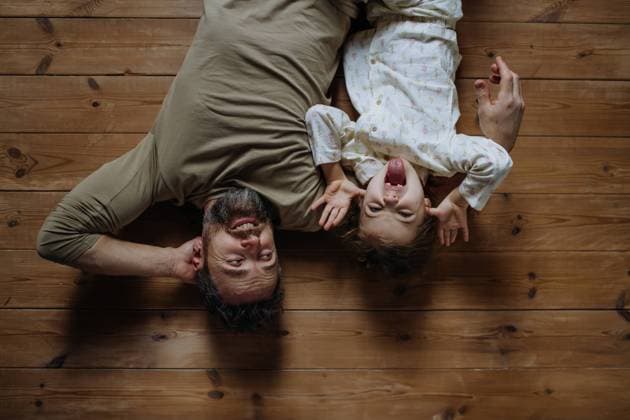 Top view of father with daughter lying on floor laughing together. Girls dad. Unconditional paternal love, Father s Day concept. Top view of father with daughter lying on floor, making faces and laughing together. Girls dad. Unconditional paternal love, Father s Day concept. model released