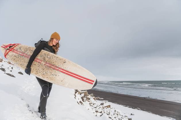 Creative Highlights Symbolbilder Woman walking on beach with surf board winter iceland Grindavik, Grindavíkurbær, Iceland CR_ALEG240222-351799-01 ,model released, Symbolfoto
