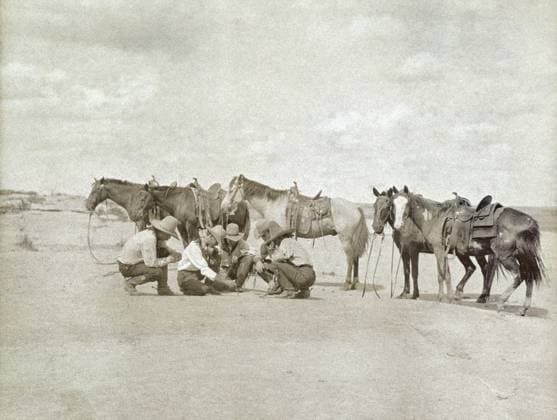 TEXAS: COWBOYS, c1907. Five cowboys gathered together as one of them draws a map on the ground beside their horses, Texas. Photograph by Erwin Evans Smith, c1907.  Copyright: xGRANGERx xGRANGERx 0124964