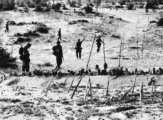 VIETNAM WAR: BEACH, 1965. U.S. Marines advancing inland through a network of obstacles, set up by local villagers under the direction of Viet Cong guerrillas, after landing on a beach on the coast of South Vietnam, about 40 miles south of Da Nang, 18 November 1965. Obstacles include bamboo spikes, and tall wooden poles connected by wires to land mines.  Copyright: xGRANGERx xGRANGERx 0176787
