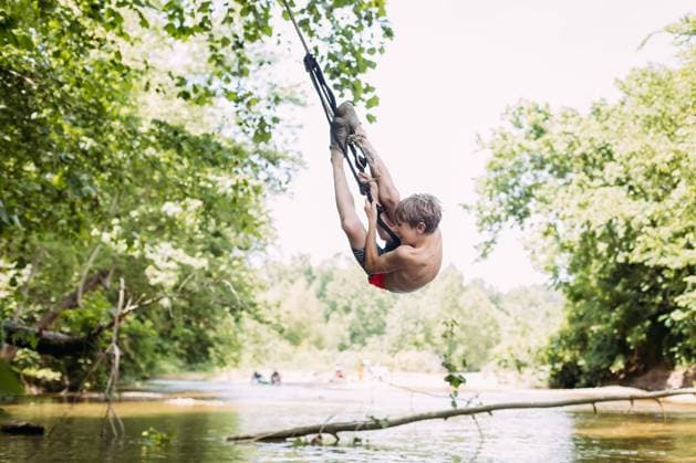Creative Highlights Symbolbilder Boy hanging on rope swing from tree during summer Millersville, Missouri, United States CR_WEKW240325C-1377597-01 ,model released, Symbolfoto