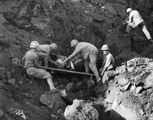 WWII: IWO JIMA, 1945. Four American Marines shifting a captured Japanese soldier onto a stretcher while another covers a cave entrance with his Browning automatic rifle. Photograph from the United States Marine Corps, 1945.  Copyright: xGRANGERx xGRANGERx 0644937