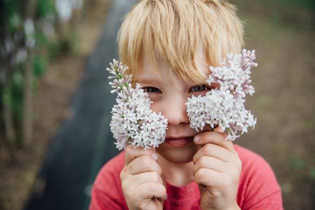 Creative Highlights Symbolbilder Portrait of boy holding lilac flowers up to face outdoors in summer United States, North Dakota, Bismarck CR_KIFR240402-1377326-01 ,model released, Symbolfoto