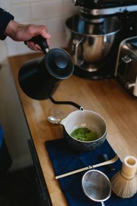 kettle pouring boiling water into matcha tea powder drink Bloomington, Indiana, United States R_QGNV240402-1384556-01 ,model released, Symbolfoto