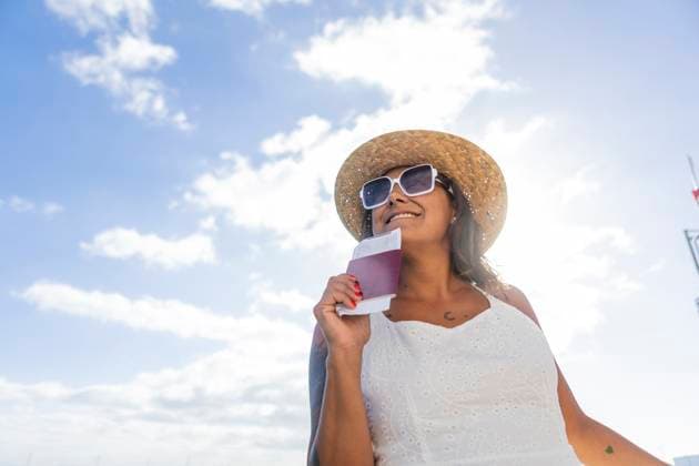 Cheerful woman in straw hat and sunglasses holding a passport, ready for a leisure trip under a sunny sky, symbolizing a carefree weekend getaway. Model Released JuanAizpuru_ID20118_595637_034 Copyright: xJuanxAizpurux