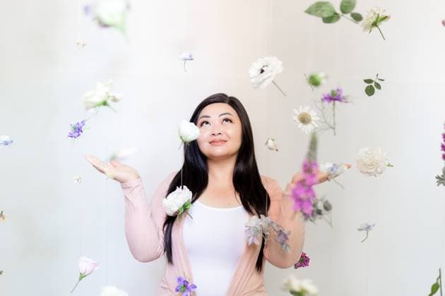 Creative Highlights Symbolbilder Smiling asian woman looking up at hanging flowers and plants Charlotte, North Carolina, United States CR_VIXP24040348-1370976-01 ,model released, Symbolfoto