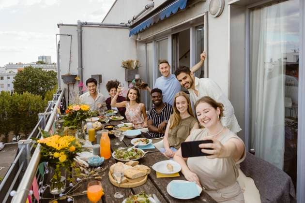 Smiling woman taking selfie with group of friends through smart phone while celebrating dinner party in balcony Germany, Berlin, model released, property released Copyright: xMaskotx , MA108136 MA108136