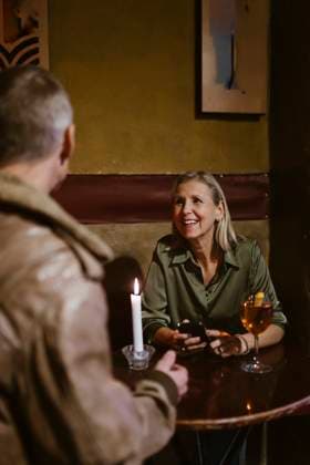 Smiling woman holding smart phone while talking with man sitting at table in restaurant Germany, Berlin, model released, property released Copyright: xMaskotx , MA108433 MA108433