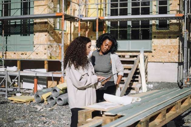 Female construction engineer discussing with client over digital table while standing in front of under construction apa Sweden, Stockholm, model released, property released Copyright: xMaskotx , MA108665 MA108665
