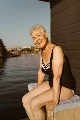 Portrait of happy senior woman wearing swimsuit while sitting near lake on houseboat Germany, Berlin, model released, property released Copyright: xMaskotx , MA108722 MA108722