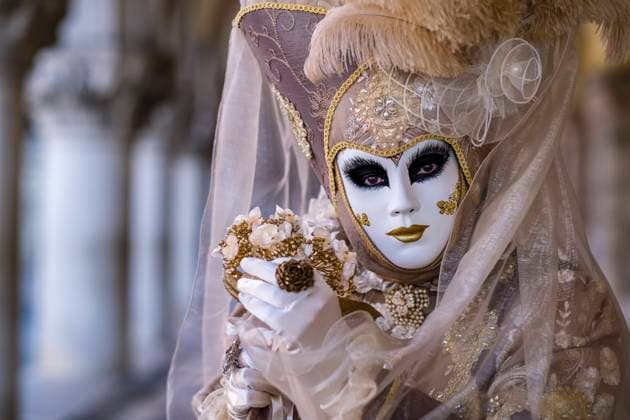 Portrait of a feminin masked person in a creative costume, posing in front of the Palazzo Ducale, celebrating the Venetian Carnival. Venice Veneto Italy FB_2024_0598